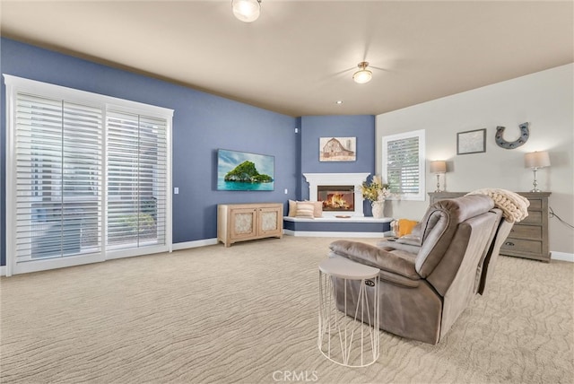 carpeted living room with baseboards and a glass covered fireplace