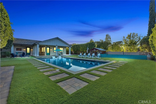 pool at dusk with a fenced in pool, fence, a lawn, and a patio