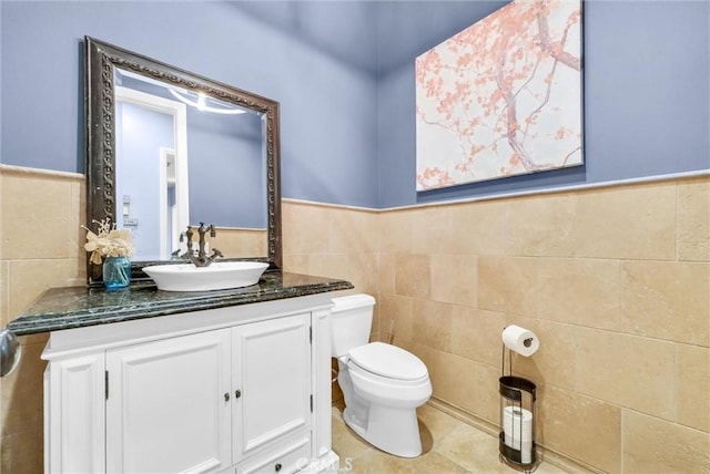 half bathroom with toilet, a wainscoted wall, and tile walls