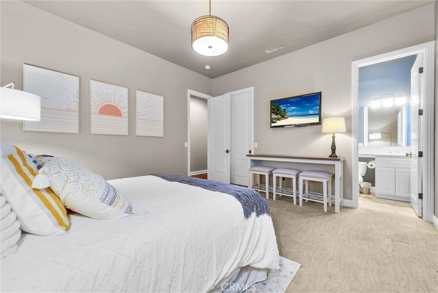 carpeted bedroom featuring ensuite bathroom, visible vents, and baseboards