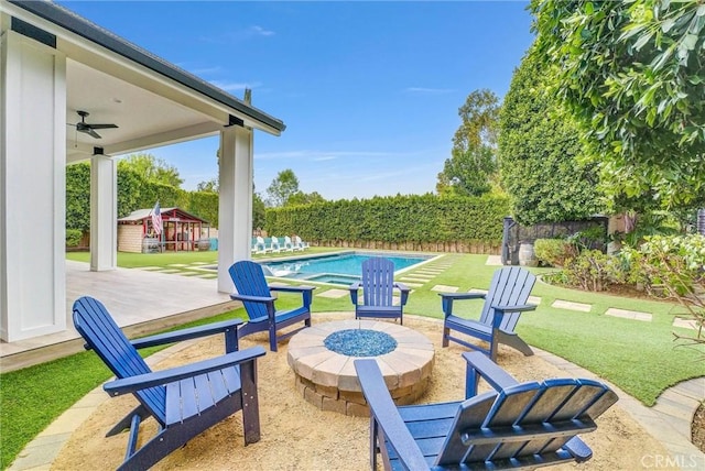 view of patio / terrace featuring a fenced in pool, fence, a fire pit, and ceiling fan