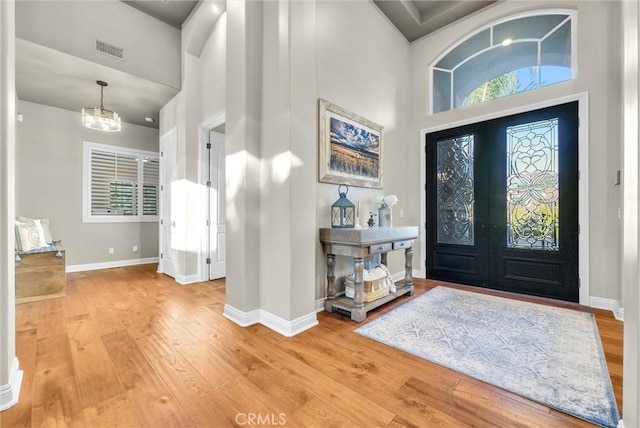 foyer entrance featuring baseboards, visible vents, light wood-style flooring, french doors, and a notable chandelier