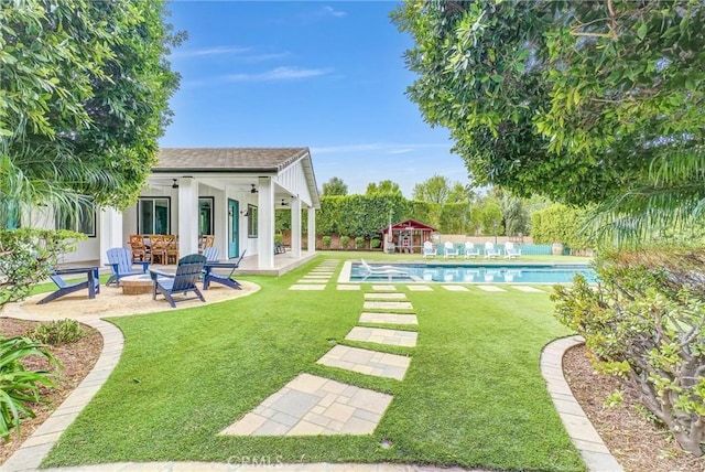 view of yard with a patio, fence, an outdoor pool, a fire pit, and an outdoor structure