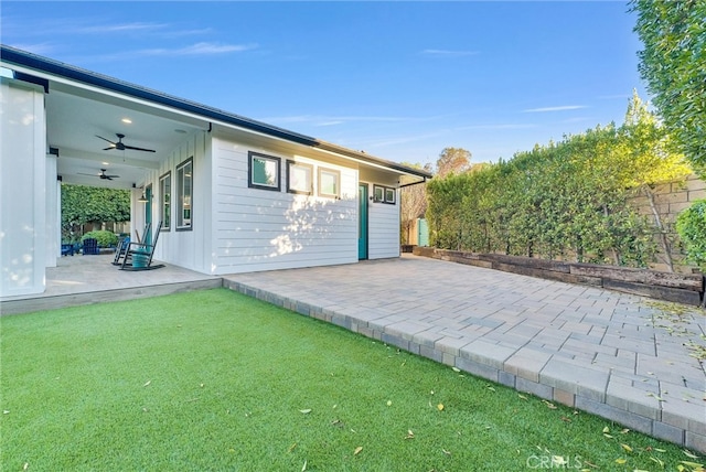 exterior space with a patio area, a lawn, and a ceiling fan