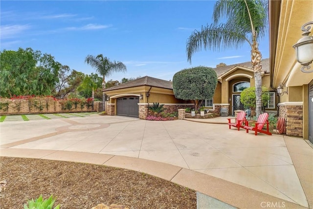 exterior space with a tile roof, fence, driveway, stone siding, and stucco siding