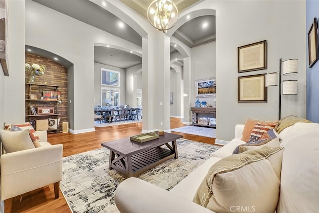 living area with baseboards, arched walkways, wood finished floors, a fireplace, and a chandelier