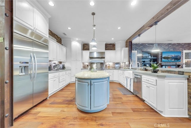 kitchen with white cabinets, appliances with stainless steel finishes, light wood-style flooring, and under cabinet range hood