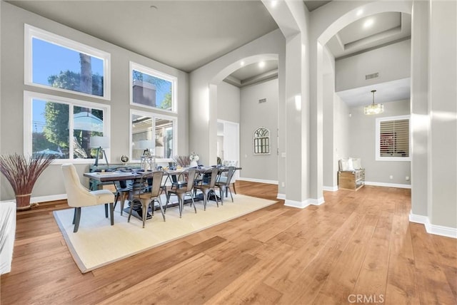 dining room with baseboards, a high ceiling, and hardwood / wood-style flooring