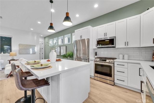 kitchen with stainless steel appliances, a center island, light wood-type flooring, and tasteful backsplash