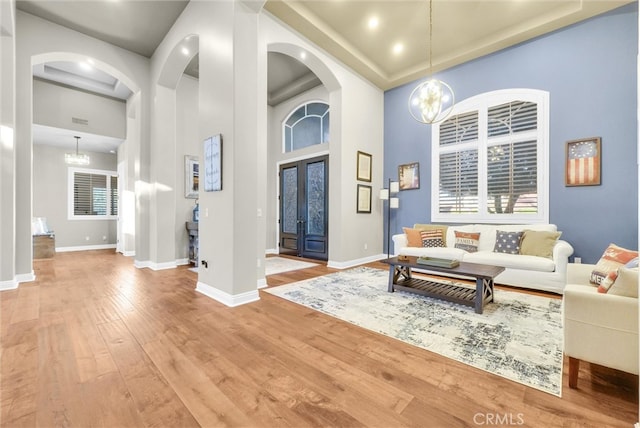 2480 Oak Ave, Corona, CA 92882 - living room featuring light wood-type flooring, arched walkways, a towering ceiling, baseboards, and a chandelier