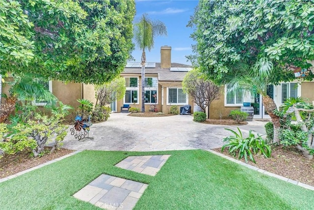 2480 Oak Ave, Corona, CA 92882 - back of house with roof mounted solar panels, a lawn, a chimney, and stucco siding