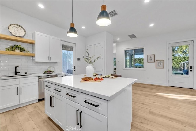 2480 Oak Ave, Corona, CA 92882 - kitchen with stainless steel dishwasher, a sink, light wood-style flooring, tasteful backsplash, and decorative light fixtures