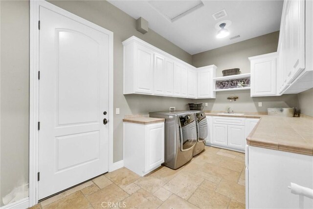 2480 Oak Ave, Corona, CA 92882 - laundry area featuring cabinet space, stone tile floors, washing machine and dryer, and baseboards