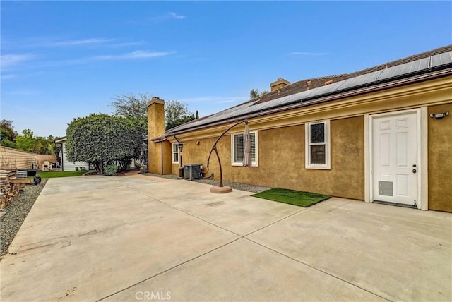 2480 Oak Ave, Corona, CA 92882 - rear view of property with cooling unit, a chimney, roof mounted solar panels, a patio area, and stucco siding