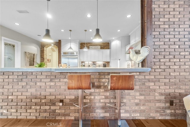 2480 Oak Ave, Corona, CA 92882 - kitchen with built in fridge, recessed lighting, white cabinets, hanging light fixtures, and a kitchen bar