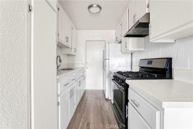 kitchen featuring under cabinet range hood, stainless steel range with gas stovetop, light countertops, wood finished floors, and a sink