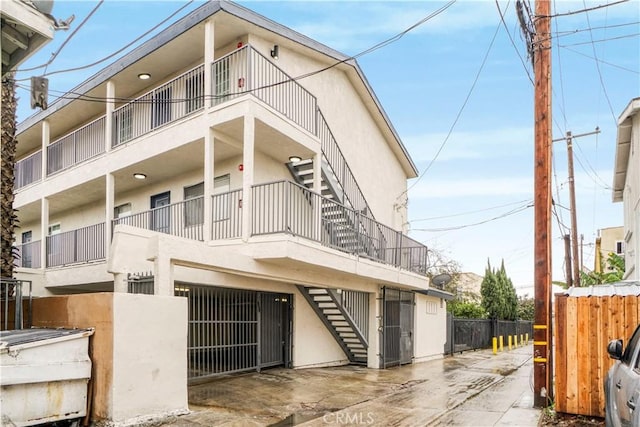 view of front of property with stucco siding, stairs, and fence