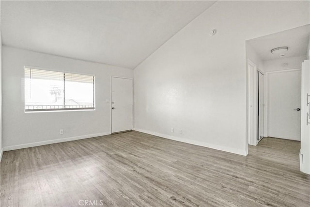 unfurnished room with baseboards, wood finished floors, and vaulted ceiling