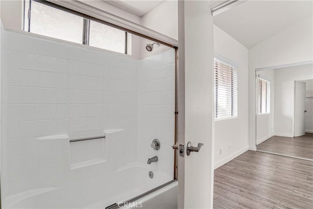 full bathroom with a wealth of natural light, vaulted ceiling, shower / tub combination, and wood finished floors