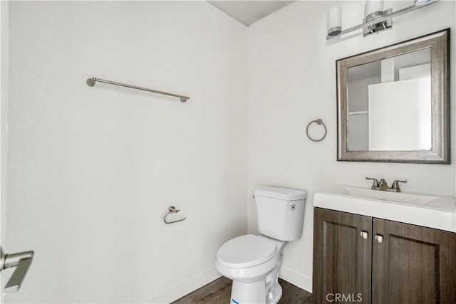 bathroom with toilet, vanity, baseboards, and wood finished floors