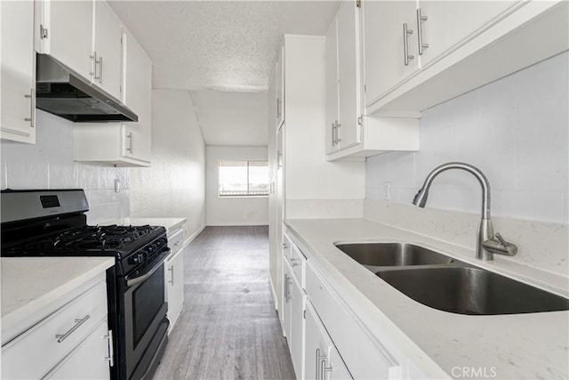 kitchen with stainless steel range with gas cooktop, under cabinet range hood, white cabinets, a textured ceiling, and a sink