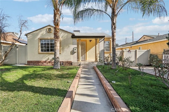 bungalow-style house featuring a front yard, fence, a gate, and stucco siding