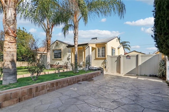 view of front of property featuring a gate, fence, concrete driveway, and stucco siding