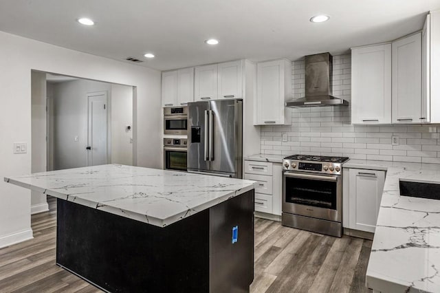 kitchen featuring stainless steel appliances, wood finished floors, visible vents, wall chimney exhaust hood, and tasteful backsplash