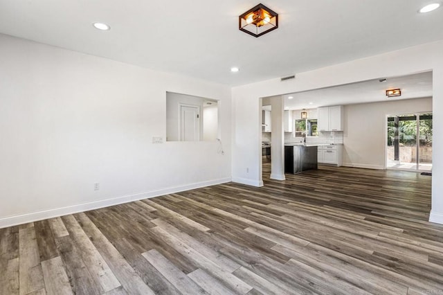 unfurnished living room with recessed lighting, dark wood-style flooring, and baseboards