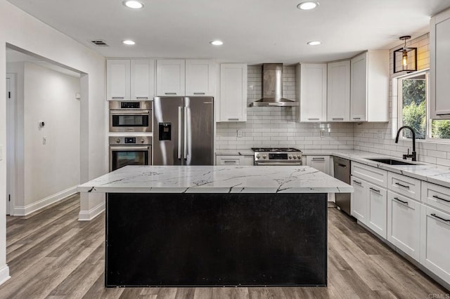 kitchen featuring tasteful backsplash, visible vents, wall chimney exhaust hood, appliances with stainless steel finishes, and a sink