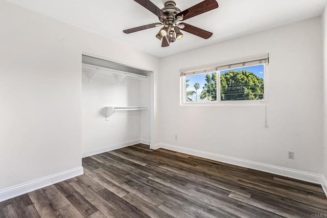 unfurnished bedroom featuring dark wood-type flooring, a closet, baseboards, and a ceiling fan