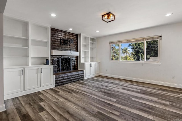 unfurnished living room featuring a large fireplace, baseboards, dark wood finished floors, and recessed lighting