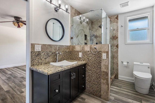 bathroom featuring toilet, a stall shower, wood finished floors, and visible vents