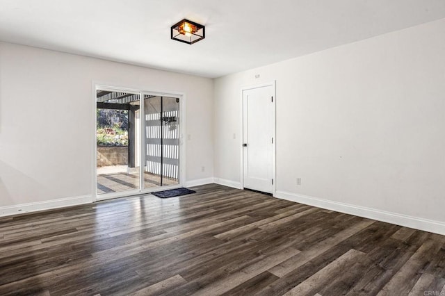 empty room featuring dark wood-style floors and baseboards