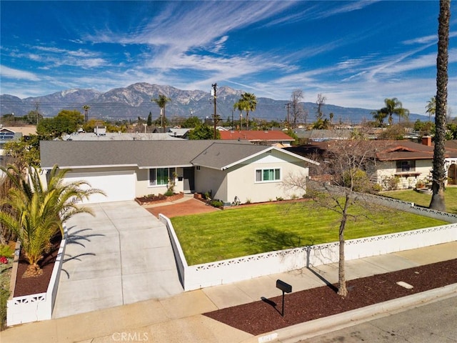 ranch-style house featuring stucco siding, an attached garage, a mountain view, fence, and a front lawn