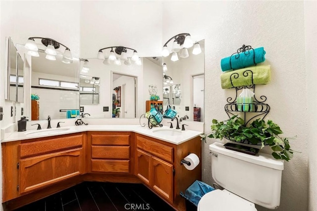 full bathroom with toilet, double vanity, and a sink