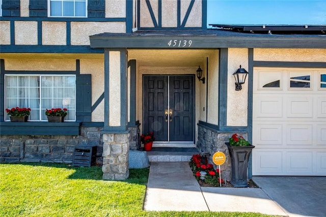 view of exterior entry featuring stone siding, an attached garage, and stucco siding