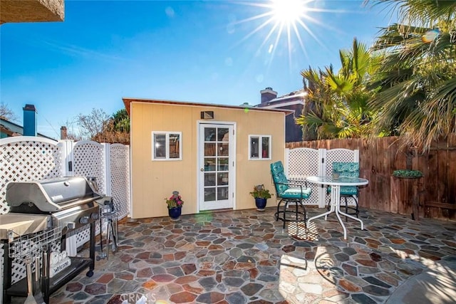 view of patio / terrace with area for grilling, fence, and an outdoor structure