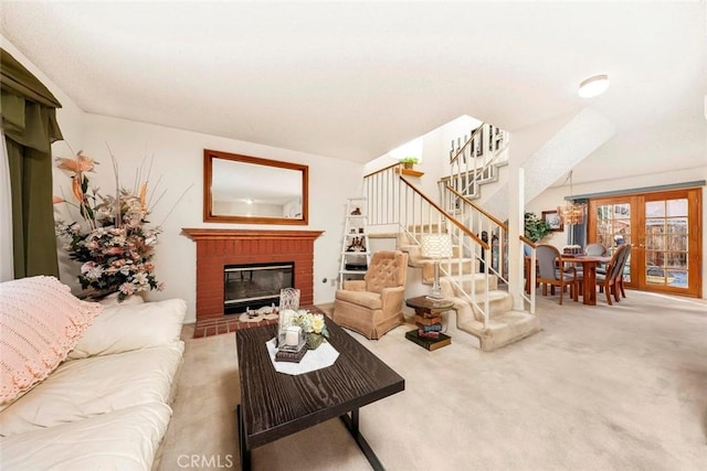 living room with a brick fireplace, carpet flooring, french doors, and stairs