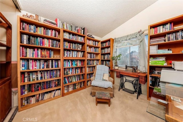 living area with lofted ceiling, carpet floors, bookshelves, and a textured ceiling