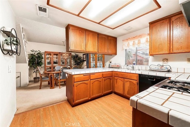 kitchen with brown cabinetry, dishwasher, and tile countertops