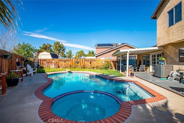 view of pool featuring a pool with connected hot tub, cooling unit, a fenced backyard, and a patio