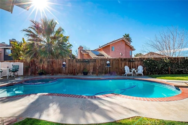 view of swimming pool featuring a patio area, a fenced backyard, and a pool with connected hot tub