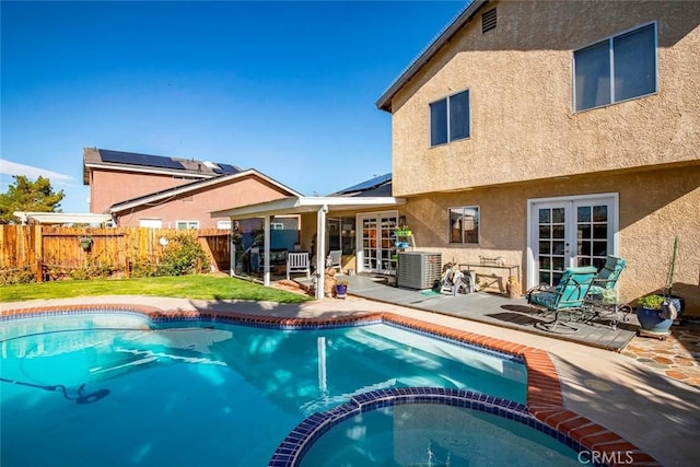 view of swimming pool with french doors, a patio area, a fenced backyard, and a pool with connected hot tub