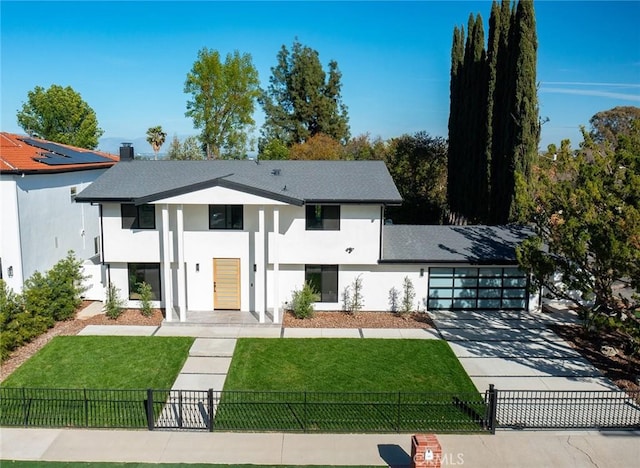 view of front of house featuring a front lawn, a fenced front yard, an attached garage, and stucco siding