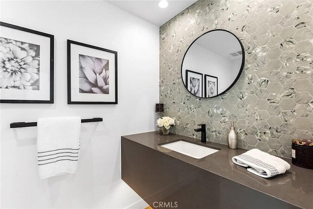 bathroom featuring visible vents, decorative backsplash, and a sink