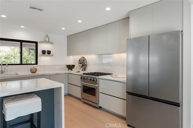 kitchen featuring tasteful backsplash, visible vents, light wood-style flooring, appliances with stainless steel finishes, and a sink