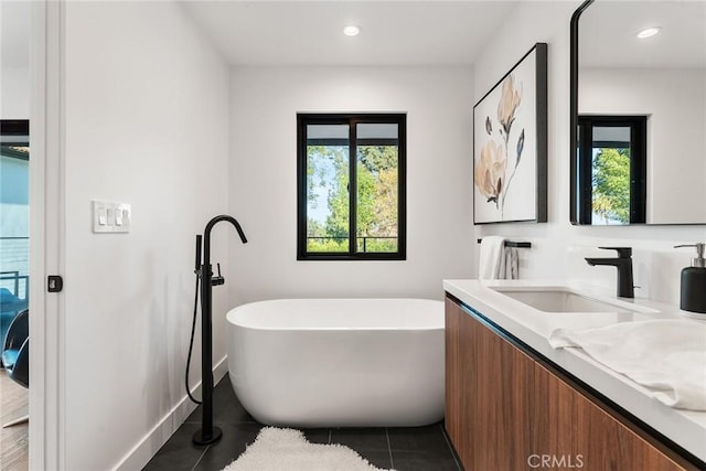 bathroom with recessed lighting, a freestanding tub, vanity, and tile patterned floors