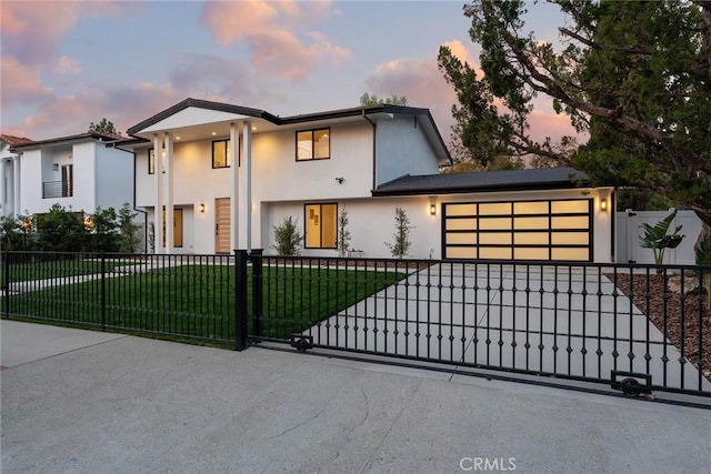 view of front facade with an attached garage, a fenced front yard, stucco siding, a yard, and driveway