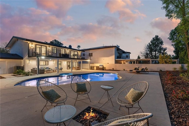 pool at dusk featuring an outdoor living space with a fire pit, fence, cooling unit, a patio, and a fenced in pool